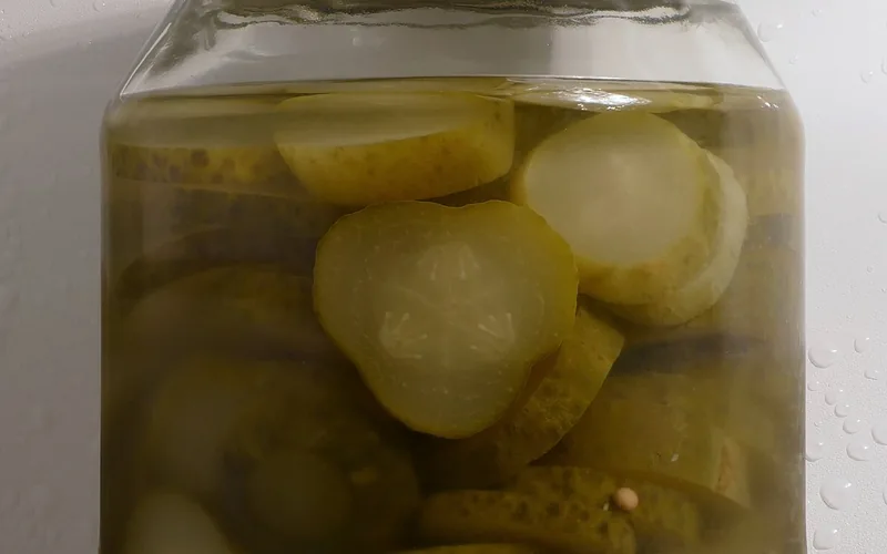 Frasco de vidrio con pepino en rodajas y tapa oscura